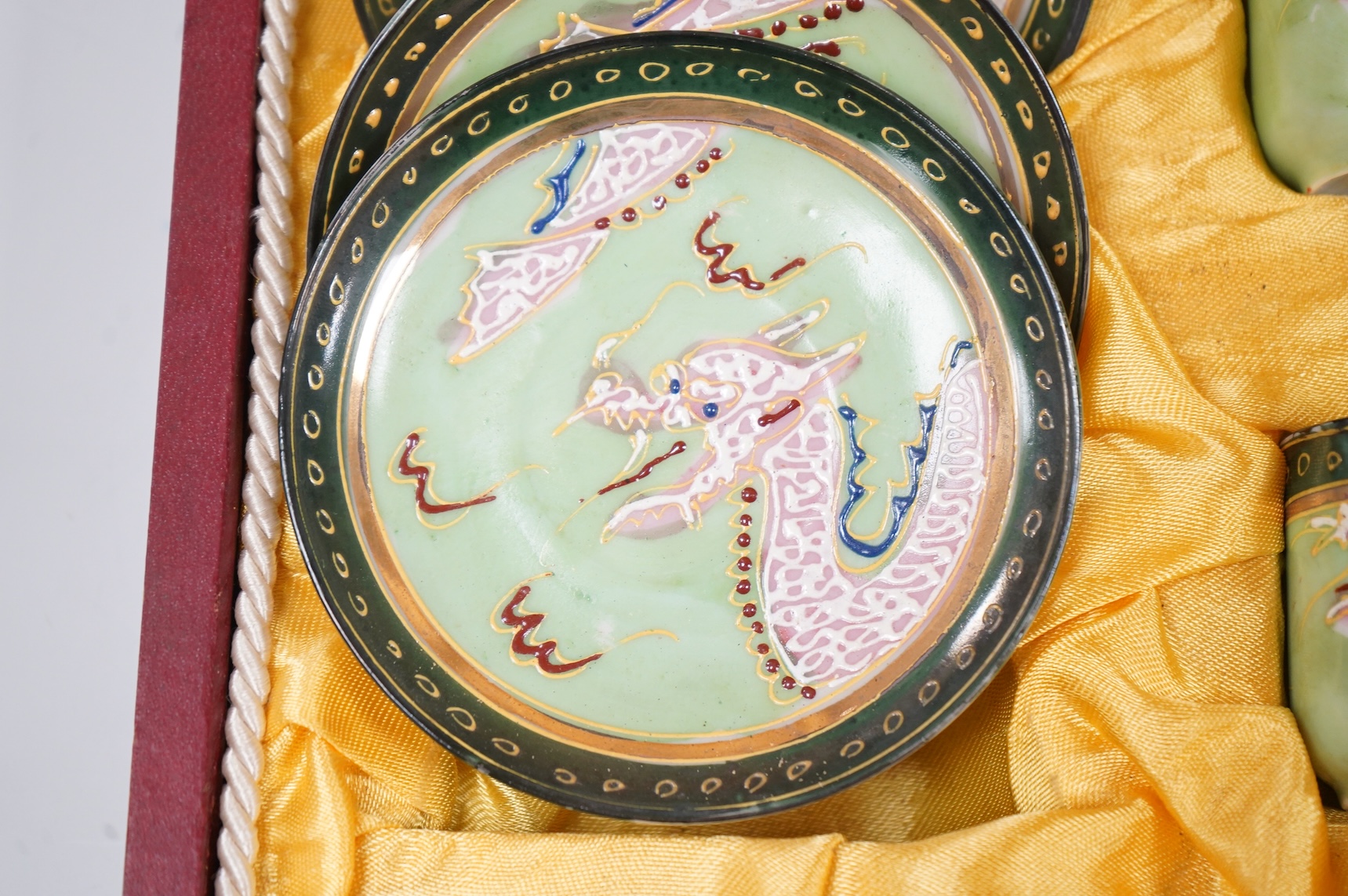 A cased Japanese coffee set, decorated with dragons on a green ground, case 34cm wide